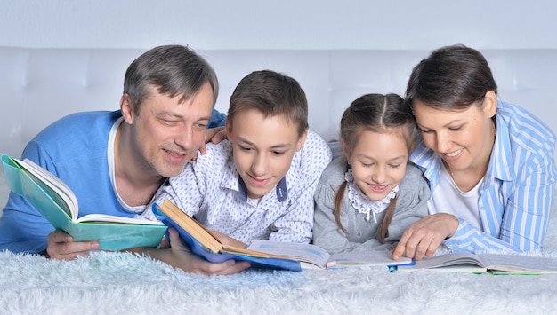 Familie liest gemeinsam Bücher auf dem Boden