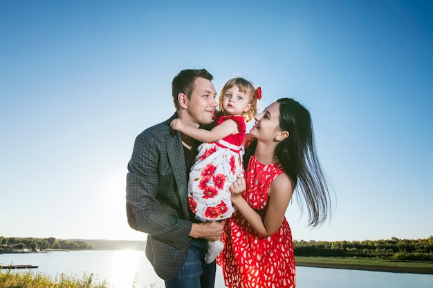 Familie, Mama, Papa halten die Tochter glücklich und schönen Sonnenuntergang Spaziergang auf dem Pier