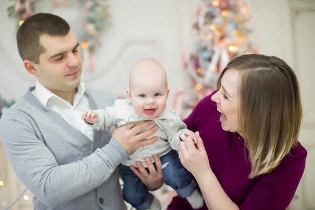 Familie mit Baby am Neujahrsbaum Mama Papa und kleiner Sohn zu Weihnachten