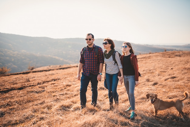 Familie mit dem Hund, der auf einem Berg wandert