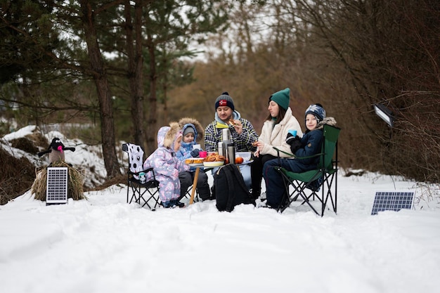 Familie mit drei Kindern im Winterwald verbringt Zeit zusammen bei einem Picknick
