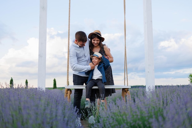 Familie mit einem Kind auf einer Schaukel in einem Lavendelfeld