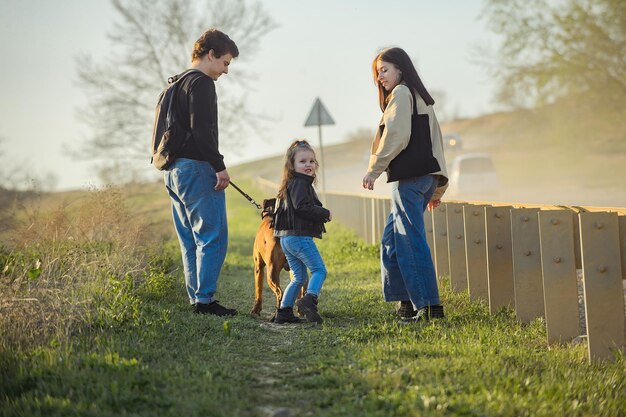 Familie mit einem Kind und einem Hund auf einem Spaziergang entlang der Straße