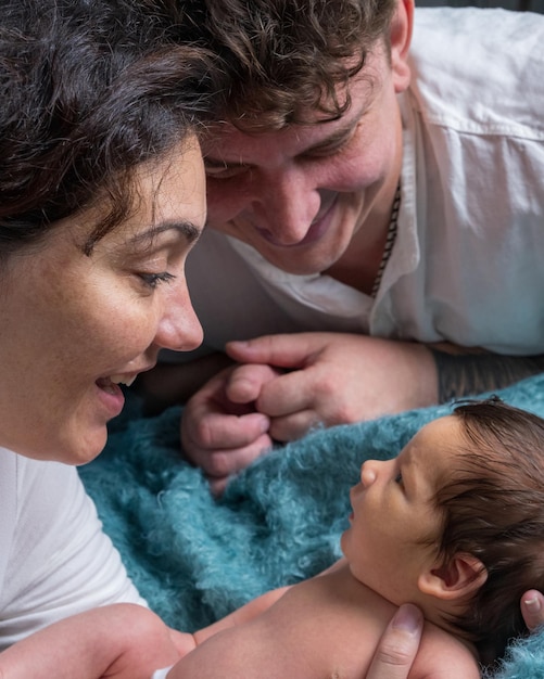 Foto familie mit einem neugeborenen baby mama und papa halten das baby in ihren armen und schauen ihren sohn an