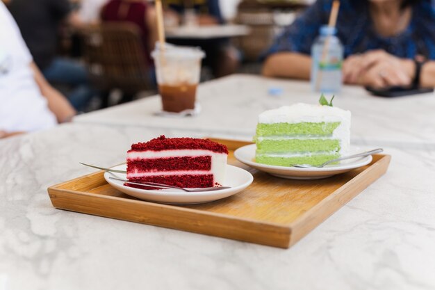 Familie mit einem stück rotem samtkuchen und grünem teekuchen im café?