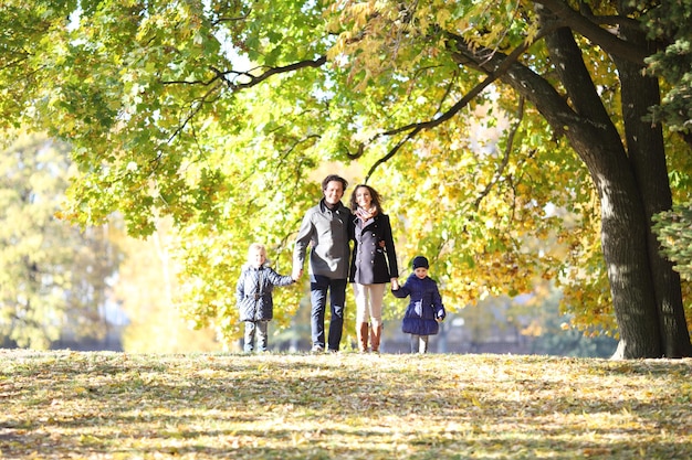 Familie mit Kindern, die im Herbstpark spazieren gehen