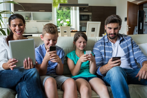 Familie mit Laptop und Handy im Wohnzimmer