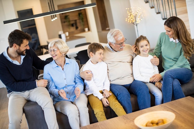 Familie mit mehreren Generationen sitzt zusammen auf dem Sofa im modernen Zuhause und sieht fern