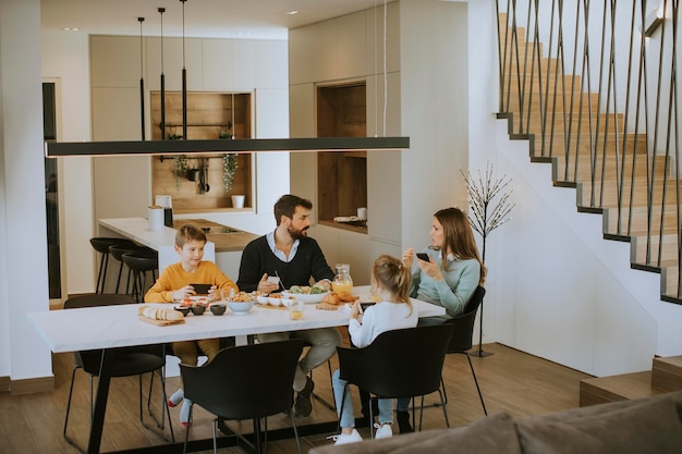 Familie mit Mobiltelefonen beim Frühstück am Esstisch in der Wohnung