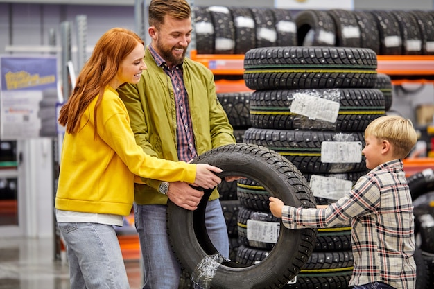 Familie mit Sohn, der Autoreifen im Laden wählt, zusammen Wahl trifft, Spaß hat, Einkaufskonzept