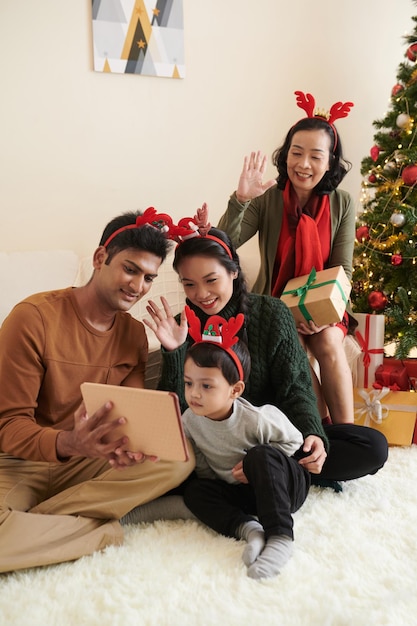 Familie mit tablet-computer, die verwandte anruft, um frohe weihnachten zu wünschen