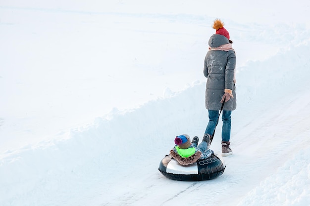 Familie Mutter und Kind Winteraktivität zusammen auf Snowtubing an