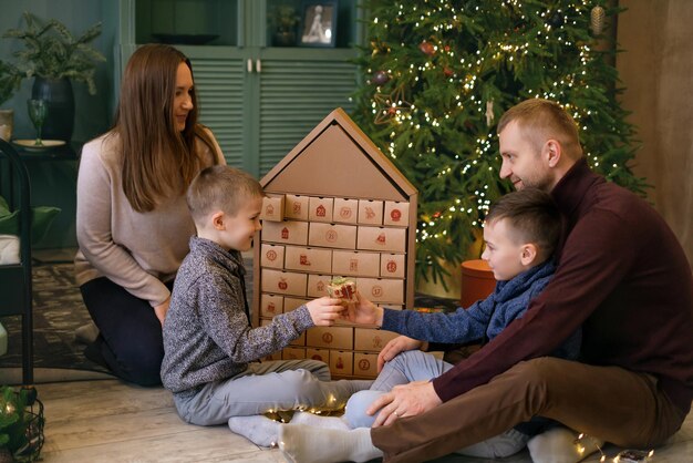 Familie öffnet Geschenke mit Söhnen am Weihnachtsbaum