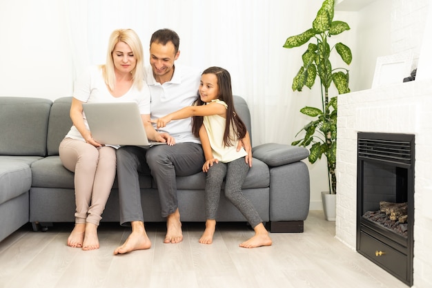 Familie online einkaufen. Glückliche Familie, die lächelt, während sie auf der Couch sitzt und zusammen online shoppt