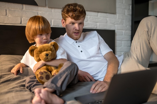 Familie. Papa arbeitet an einem Laptop, während sein Sohn neben ihm spielt