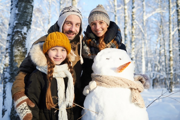 Familie posiert mit Schneemann