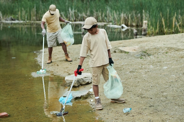 Familie reinigt gemeinsam im Freien Wasser vom Müll