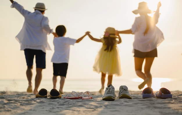 Familie, Reisen, Strand, Entspannung, Lifestyle, Urlaubskonzept. Familie, die ein Picknick genießt. Eltern halten ihre Kinder an den Händen und gehen im Urlaub bei Sonnenuntergang am Strand spazieren.