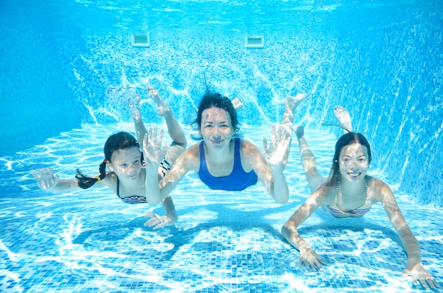 Familie schwimmt im Pool unter Wasser, glückliche aktive Mutter und Kinder haben Spaß unter Wasser, Fitness und Sport mit Kindern in den Sommerferien im Resort