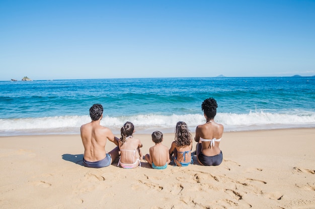 Foto familie sitzt auf dem sand