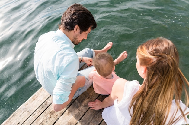 Foto familie sitzt auf wasser hängenden füßen im teich, blick von oben