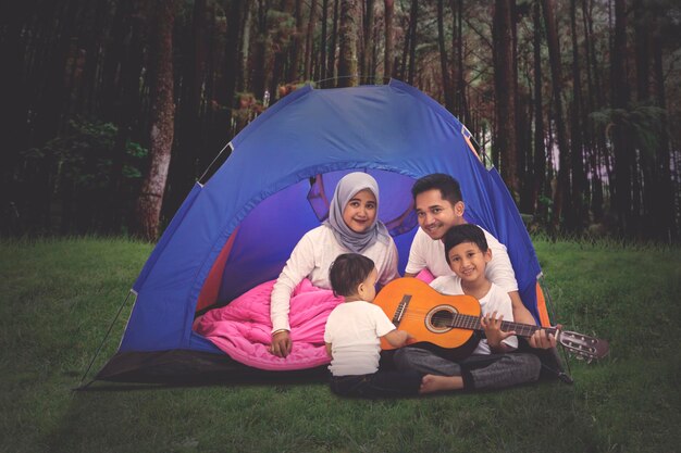 Familie spielt Gitarre im Campingzelt im Wald