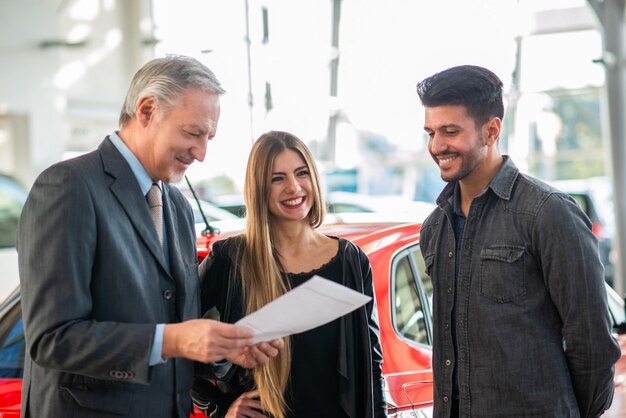 Familie spricht mit dem Verkäufer und wählt ihr neues Auto in einem Ausstellungsraum aus