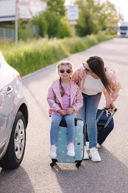 Familie steht neben dem Auto mit Koffern und wartet auf die Reise Mutter und Tochter bereiten sich auf die Reise vor