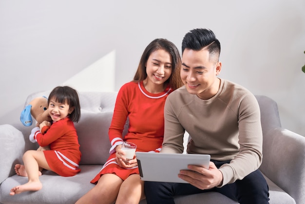 Familie, Technologie, Elternschaft und Menschenkonzept - glückliche Mutter und Vater, die der kleinen Tochter zu Hause Tablet-PC-Computer zeigen