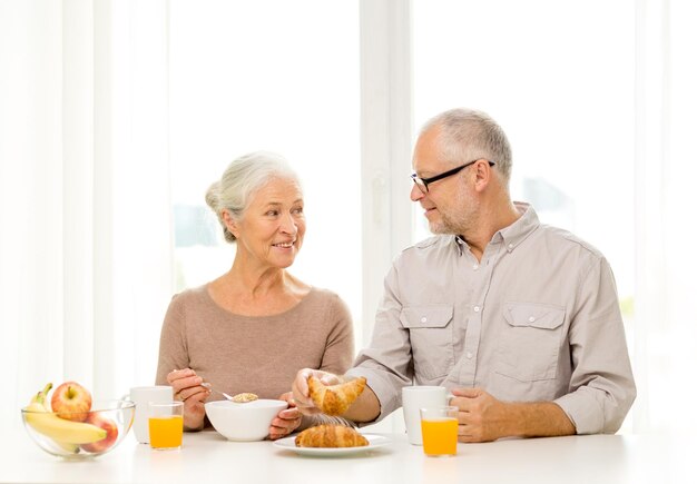 familie, technologie, essen, getränke und personenkonzept - glückliches seniorenpaar, das zu hause frühstückt