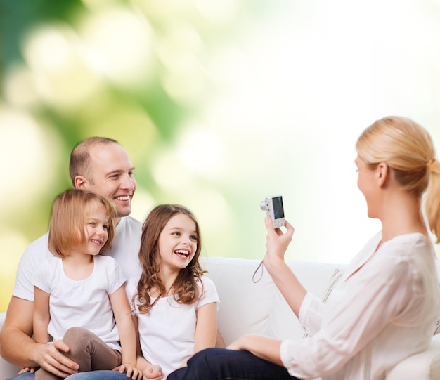 Familie, Technologie, Ökologie und Menschen - lächelnde Mutter, Vater und kleine Mädchen mit Kamera auf grünem Hintergrund