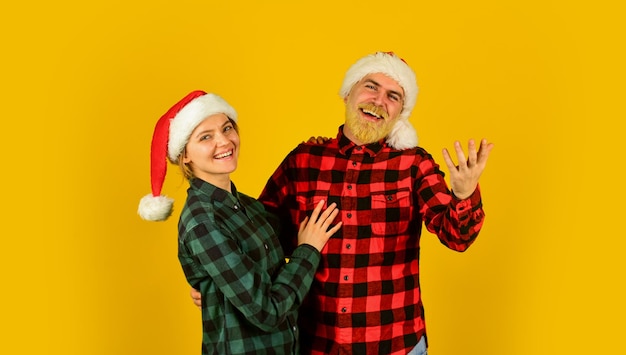 Familie tragen Weihnachtsmützen Unterhaltungsideen für Erwachsene Weihnachtsmann-Team Liebespaar gelber Hintergrund Weihnachtszauberzeit Wir lieben Weihnachten Verliebte Paare genießen Weihnachtsfeiertagsfeier