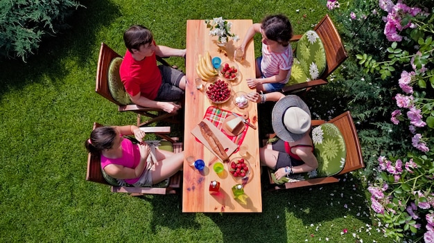 Familie und Freunde essen zusammen im Freien auf einer Sommergartenparty