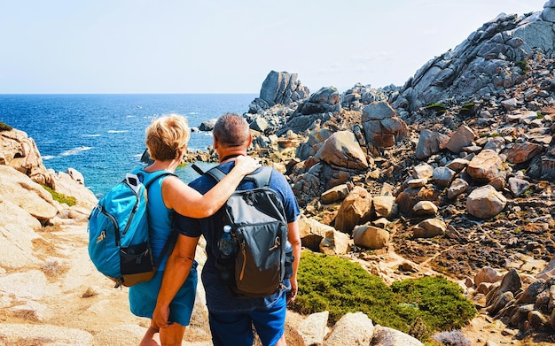 Familie und Landschaft mit felsiger Küste von Capo Testa in Santa Teresa Gallura am Mittelmeer auf der Insel Sardinien im Sommer Italien. Paar und Landschaft der Provinz Cagliari. Gemischte Medien.