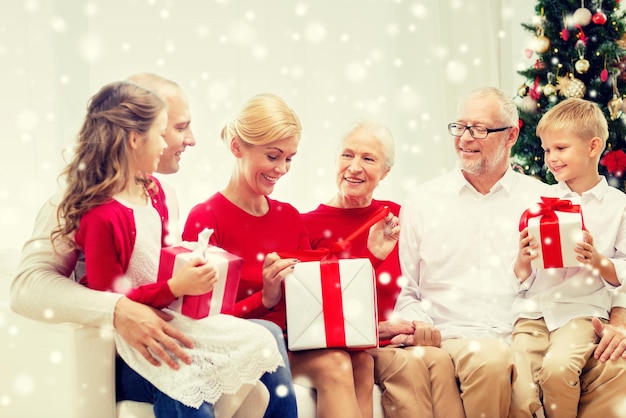 familie, urlaub, generation, weihnachten und personenkonzept - lächelnde familie mit geschenkboxen, die zu hause auf der couch sitzen