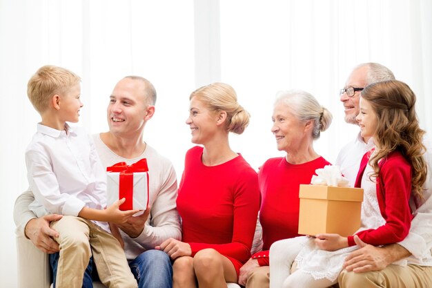 familie, urlaub, generation, weihnachten und personenkonzept - lächelnde familie mit geschenkboxen, die zu hause auf der couch sitzen