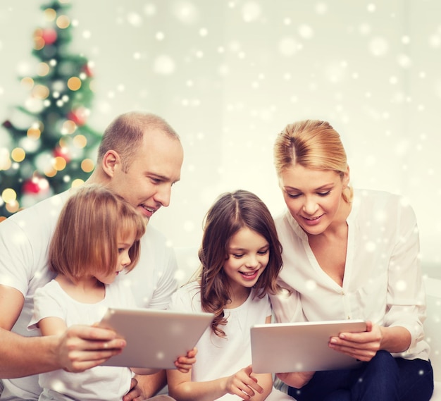 Familie, Urlaub, Technik und Menschen - lächelnde Mutter, Vater und kleine Mädchen mit Tablet-PC-Computern zu Hause