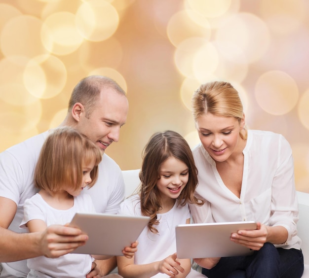 Familie, Urlaub, Technologie und Menschen - lächelnde Mutter, Vater und kleine Mädchen mit Tablet-PC-Computern über beigefarbenem Hintergrund