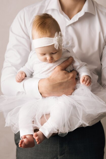 Familie, Vaterschaft und Menschenkonzept-glücklicher Vater, der kleine Tochter auf hellem Hintergrund hält