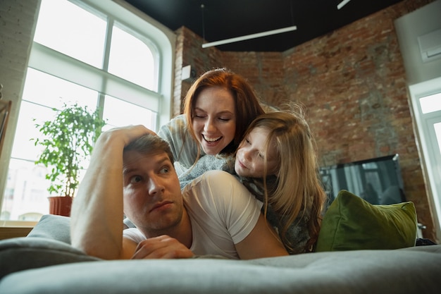 Familie verbringt schöne Zeit zu Hause, sieht glücklich und fröhlich aus und liegt zusammen