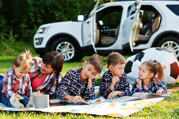 Familie verbringt Zeit zusammen Mutter mit vier Kindern im Freien in Picknickdecke gegen ihren amerikanischen Geländewagen