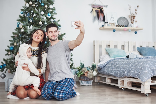 Familie versammelte sich um einen Weihnachtsbaum, der ein selfie machte