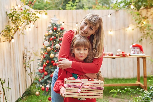 Familie Weihnachten im Juli Porträt eines Mädchens in der Nähe von Weihnachtsbaum mit Geschenken, die Kiefer Winter schmücken