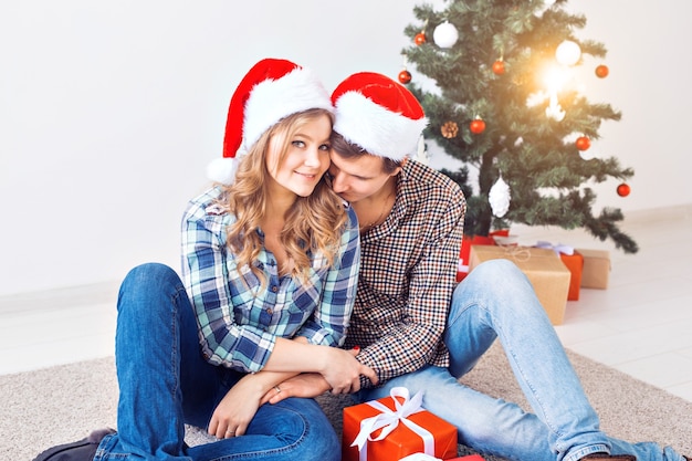 Familie, Weihnachten, Winterferien und Menschenkonzept - glückliches Paar, das sich zu Hause in der Nähe des Weihnachtsbaums umarmt.