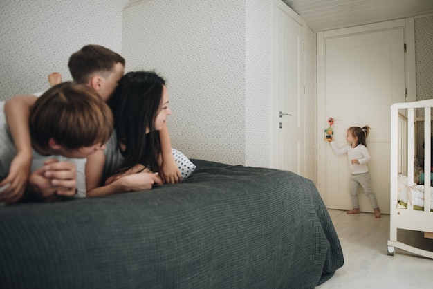 Familie zu Hause im Pyjama. Tochter und Sohn. Am Morgen aufwachen. Umarmen und Küssen im Schlafzimmer auf dem Bett.