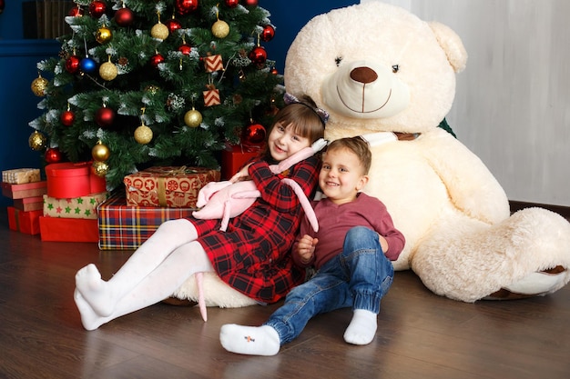 Familie zu Weihnachten mit Teddybär unter Weihnachtsbaum Weihnachtsgeschenkboxen und Dekoration