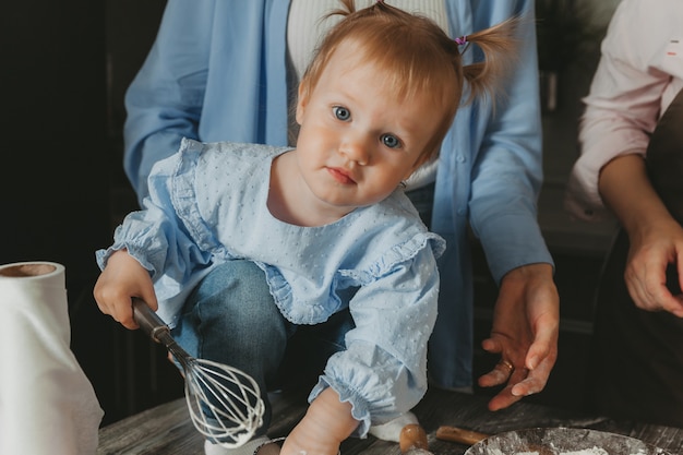 Foto familie: zwei frauen und kinder bereiten in der küche einen geburtstagskuchen vor.