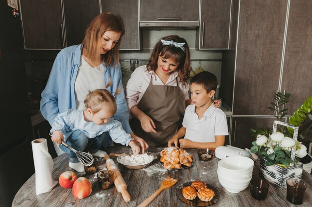 Familie: Zwei Frauen und Kinder bereiten in der Küche einen Geburtstagskuchen vor.