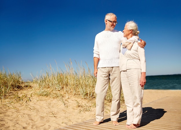 familien-, alters-, reise-, tourismus- und menschenkonzept - glückliches seniorenpaar, das am sommerstrand spricht