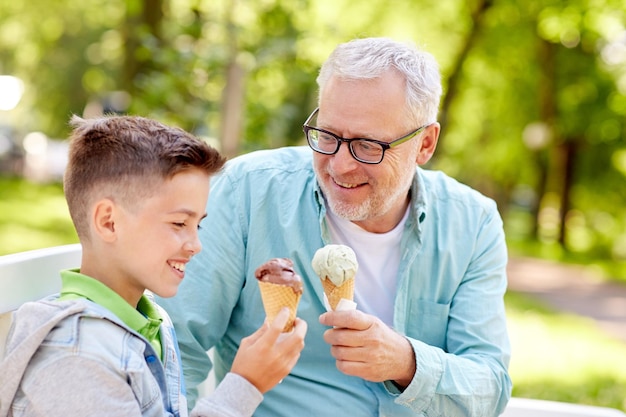 Familien-, Generations-, Kommunikations- und Menschenkonzept - glücklicher Großvater und Enkel beim Eisessen im Sommerpark